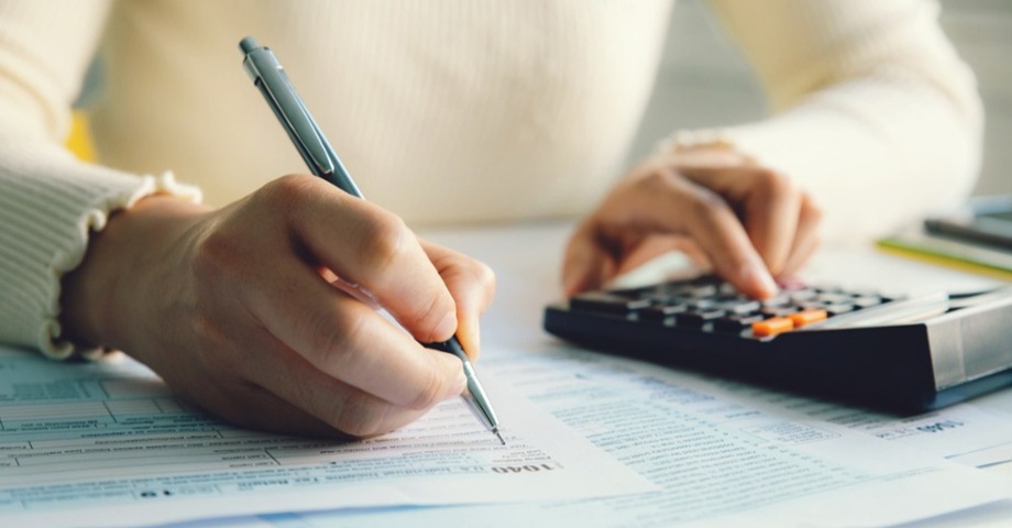 woman writing and using a calculator