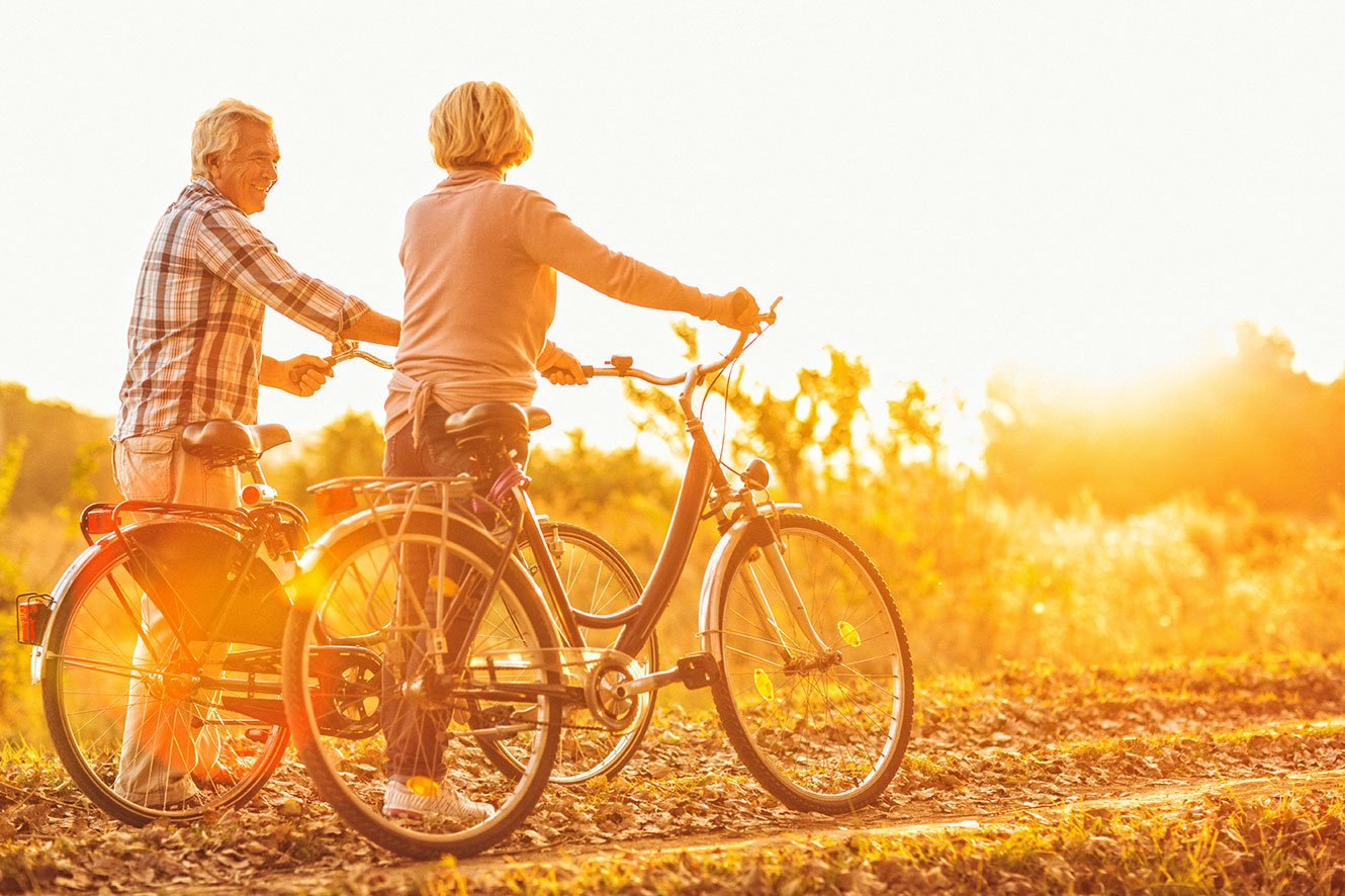 older couple riding bikes during sunset